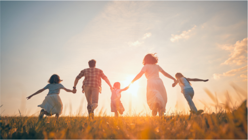 Family of five walking together in a field at sunset